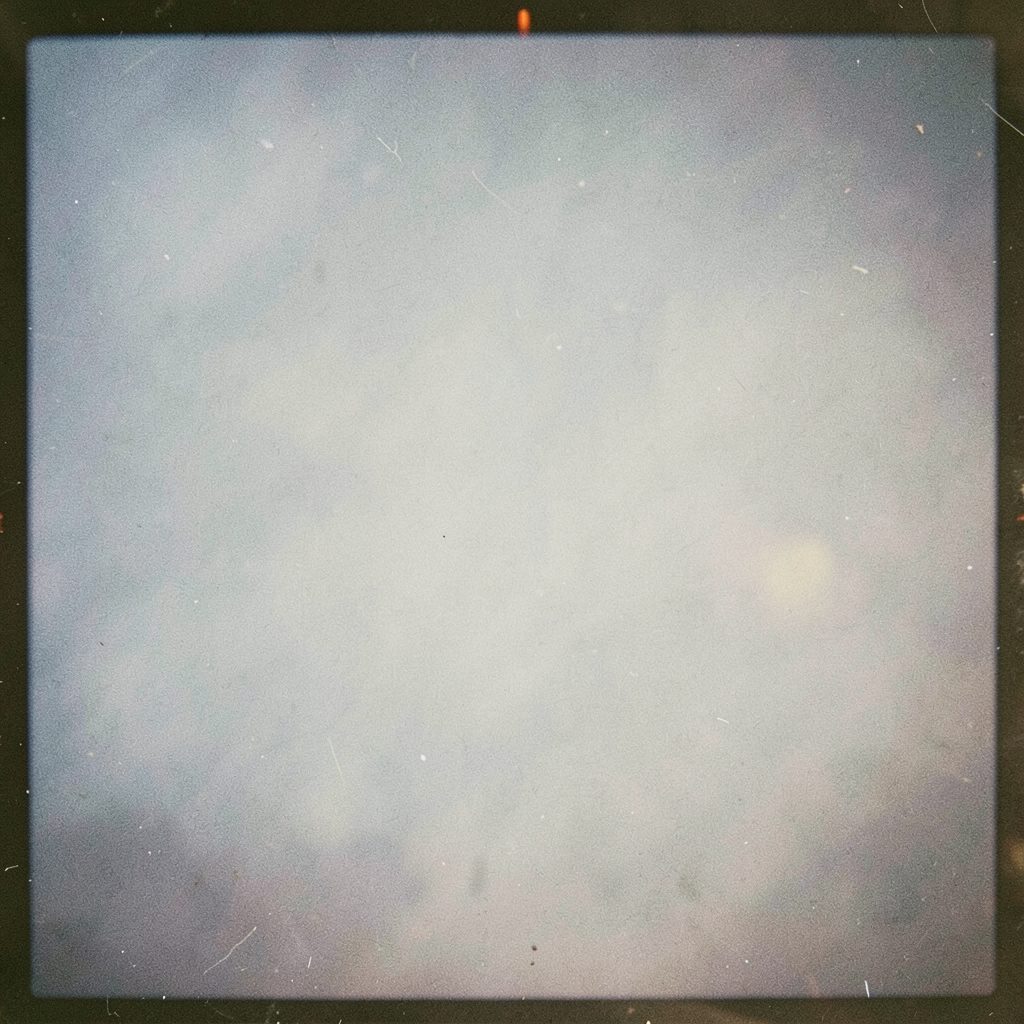 A grainy analog film photograph with warm muted colors showing a small informal group scene, relaxed everyday mood